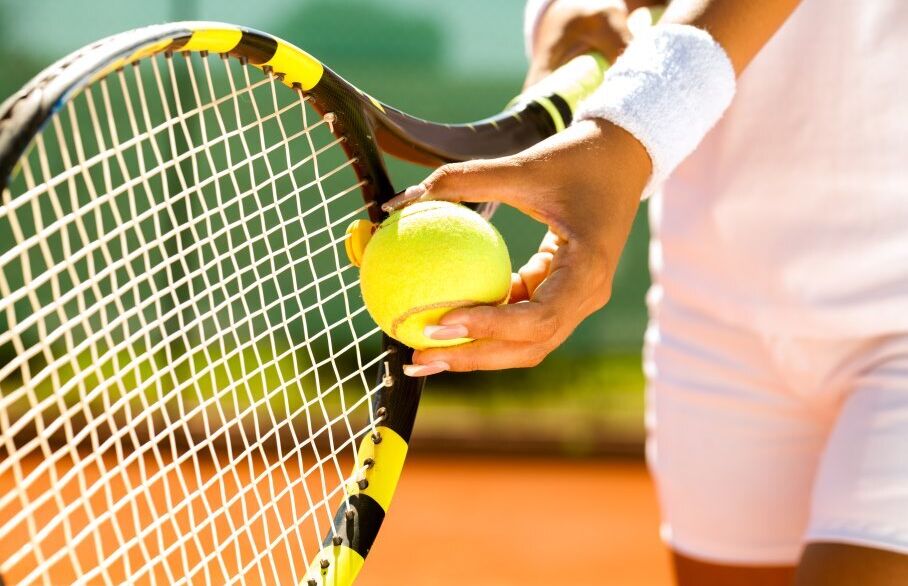 Player's hand with a tennis ball preparing to serve