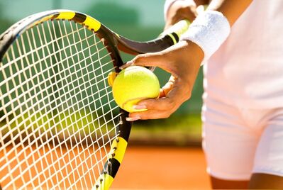 Player's hand with a tennis ball preparing to serve