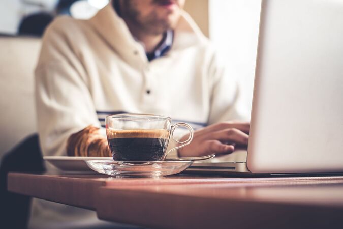 man using his laptop with a cup of coffee next to him